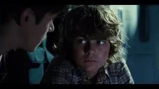 Young boy looking at man in dim room — Jurassic World