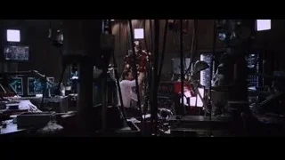Robot-like figure in workshop with monitors — Iron Man