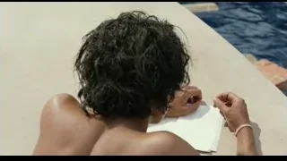 Shirtless man sitting by pool looking at paper — Life of Pi