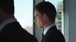 two men in suits by window overlooking cityscape — Suits
