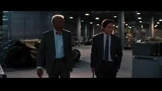 two men in suits in large room — Batman: The Dark Knight Rises
