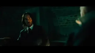man in suit sitting in dark room — John Wick: Chapter 4