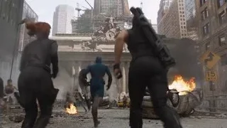 Three characters walking past burning city building — The Avengers