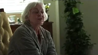 Elderly woman clapping hands in living room — Suits