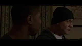 two men facing each other in dimly lit room — Creed