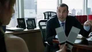 Man in suit conversing at office desk with city view — Suits