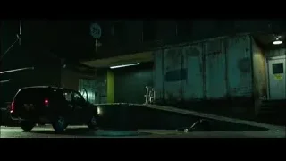 person lying on ground next to car dark alleyway — John Wick