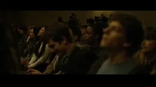 People listening in dimly lit room — The Social Network