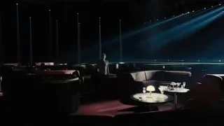Man standing in dimly lit room facing stage — Blade Runner 2049