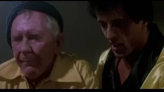 two men in yellow jackets conversing tensely — Rocky III