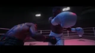 man throwing punch in dimly lit boxing ring — Creed 3