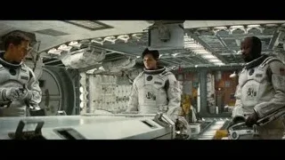 astronauts conversing in space station, one with gun — Interstellar