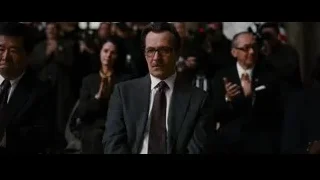 man in suit serious in crowded room — Batman: The Dark Knight Rises