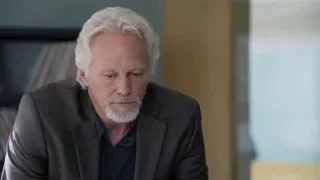 Older man with beard by bookshelf — Suits
