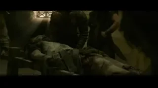 Dead body on stretcher in dark stone room — Gladiator 2