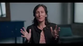 Woman with dark hair gesturing by blue cabinet — The Social Dilemma
