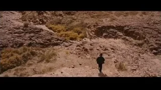 person walking on rocky desert trail — Batman: The Dark Knight Rises