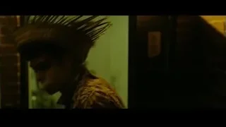 man in feathered hat by brick wall — The Social Network