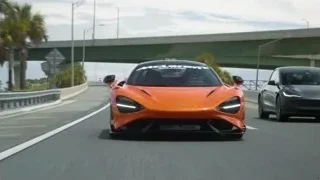 orange McLaren sports car driving on highway — Sports Cars
