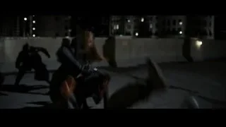 woman crouching on city rooftop at night — Batman: The Dark Knight Rises