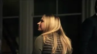 Man and woman standing in dimly lit room — Suits