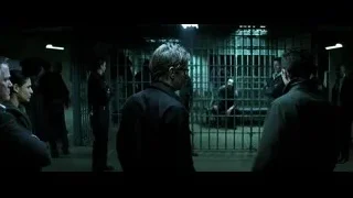 men talking in dark room with metal gate — Batman: The Dark Knight