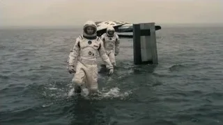 astronauts walking in ocean towards pier — Interstellar
