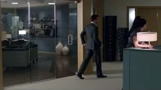 Man in suit walking towards woman at office desk — Suits