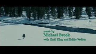 Person walking on snowy field by river — Into the Wild