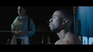 woman and man in dimly lit room — Creed 2