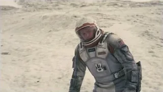 Man in NASA space suit on sandy terrain — Interstellar