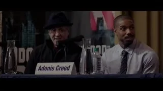 Men speaking into microphones at table — Creed