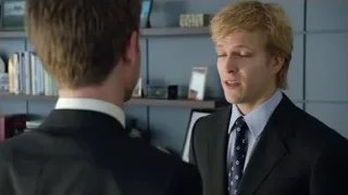 two men in suits conversing in library — Suits