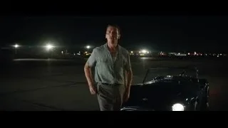Man in green shirt in front of sports car at night — Ford v Ferrari