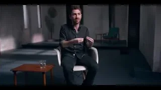 man in black shirt gesturing in concrete room — The Social Dilemma