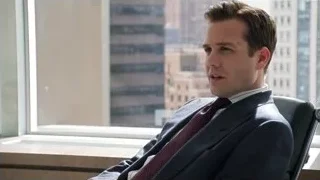 man in suit sitting by city window — Suits