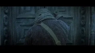 person in cloak in front of carved door — Batman