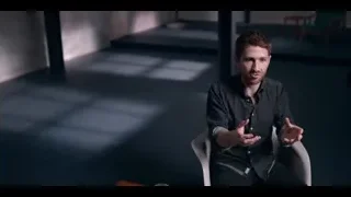 man gesturing in white armchair in dim room — The Social Dilemma