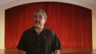 Man speaking in front of red curtain — Screened Out
