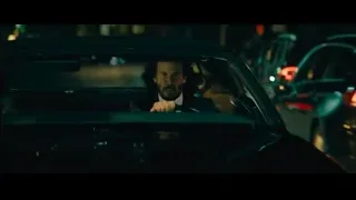 man driving car on city street at night — John Wick: Chapter 4