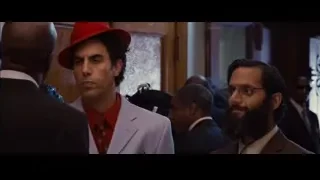 men in suits talking in a chandelier room — The Dictator