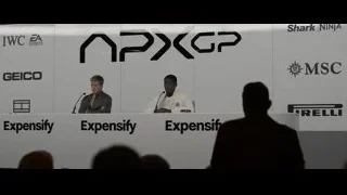 two men giving speech with company logos — F1