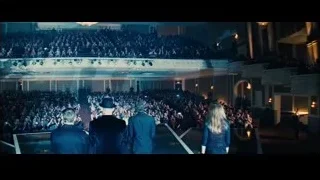 large auditorium with lit stage and crowd — Now You See Me