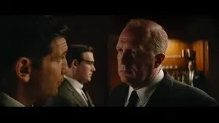 three men in suits conversing in bar — Ford v Ferrari
