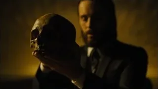 Man in suit holding skull in dim room — Blade Runner 2049