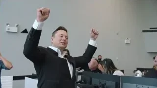 man in suit giving presentation monitors — Elon Musk: Return to Space