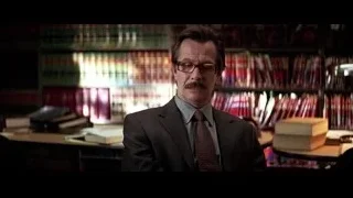 Man in suit standing before bookshelf — Batman: The Dark Knight