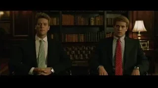 two young men in suits by bookshelf — The Social Network
