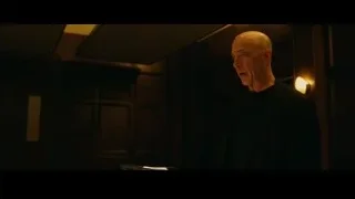 Bald man in black suit deep in thought in dimly lit room — Whiplash