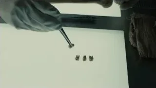 gloved hand using tweezers on dental implants — Blade Runner 2049
